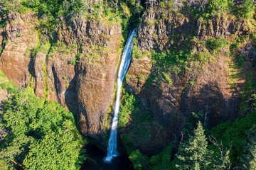a large waterfall running down the side of a mountain covered in trees