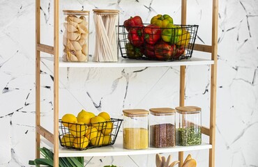 Minimalist pantry rack with fresh lemons, peppers, and glass containers filled with pasta and grains