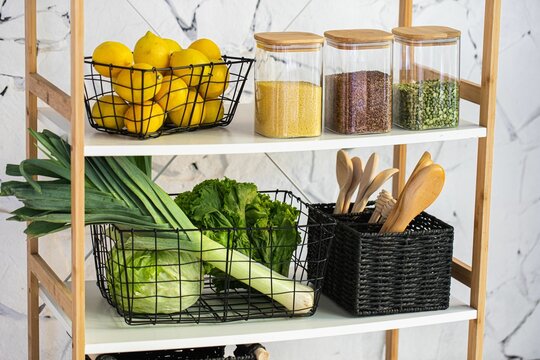 Closeup of a rack with lemons, greenery, wooden kitchen utensils, and grains in glass containers