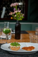 Close-up of an appetizer arrangement of a sourdough bun, spring onion, and a heart-shaped waffle