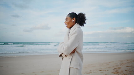 Ocean woman talking phone wireless earphones on go. African american enjoy beach