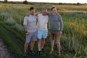 Three men, friends, laughing, standing hugging