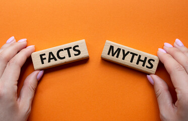 Facts or Myths symbol. Concept word Facts or Myths on wooden blocks. Businessman hand. Beautiful orange background. Business and Facts or Myths concept. Copy space