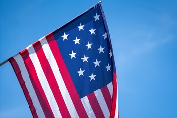 Closeup of the American flag on a pole, fluttering in the wind, the concept of the national identity