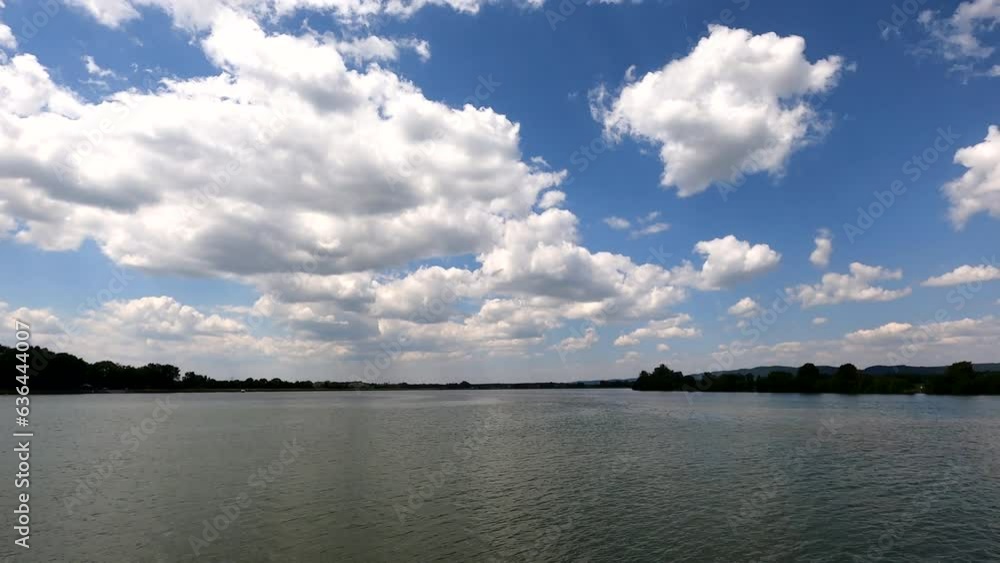 Poster landscape timelapse scene of moving clouds over a river with trees around