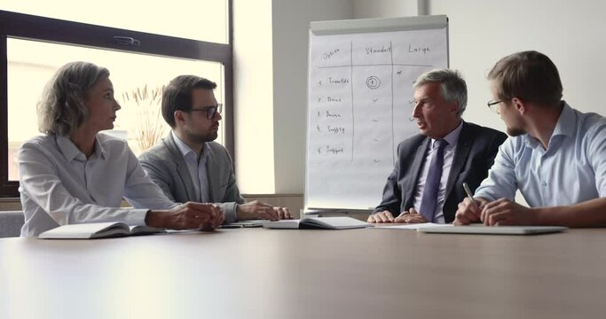 Senior business leader, executive man meeting with team in boardroom, talking to employees, discussing supply package, speaking with hands gestures, explaining work plan, giving instruction, task