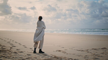 Calm woman contemplating ocean on empty quiet beach. Pensive model posing sea