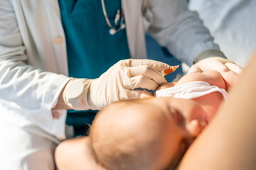Unidentified doctor wearing protective gloves giving injection to newborn in hospital. Medical...