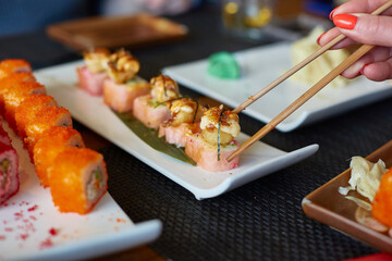 A woman's hand takes Japanese fish rolls