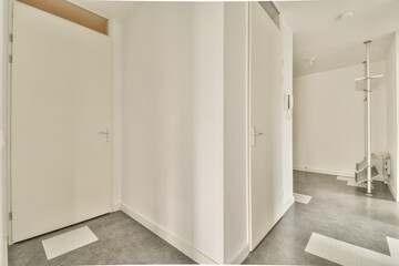 the inside of a room with white walls and grey flooring on the left side of the room is an open door