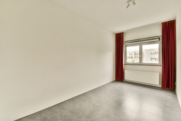 an empty room with white walls and red drapes hanging from the window in it's right hand side