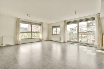 an empty living room with large windows and floor tiles on the floor, there is no one person in it