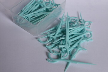 Green color dental floss pick on the white background