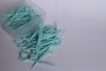Green color dental floss pick on the white background