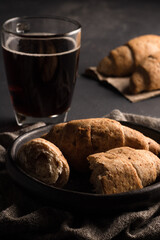 Traditional colombian food, Croissants and Handmade Corn and Flour Breads on a black plate served on a dark table, accompanied by hot black coffee.