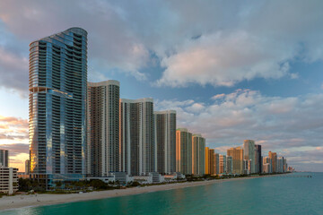 Expensive highrise hotels and condos over sandy beachfront on Atlantic ocean shore in Sunny Isles Beach city at sunset. American tourism infrastructure in southern Florida