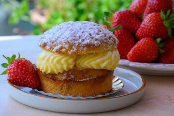 Tarte tropezienne or La Tarte de Saint-Tropez - dessert pastry consisting of filled brioche with cream and fresh berries served outdoor with fresh ripe strawberry