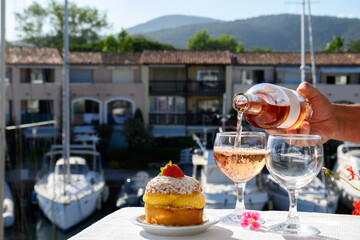 Wine and cake of French Riviera, glasses of cold rose Cote de Provence wine and Tarte Tropezienne cake in yacht harbour of Port Grimaud, summer vacation  in Provence, France.