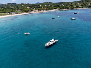 Aerial view on boats, crystal clear blue water of legendary Pampelonne beach near Saint-Tropez, summer vacation on white sandy beach of French Riviera, France