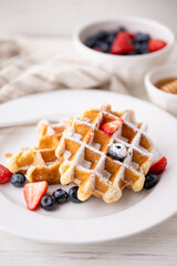 half eaten belgium waffle with strawberry, blueberry and honey