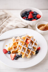 half eaten belgium waffle with strawberry, blueberry and honey