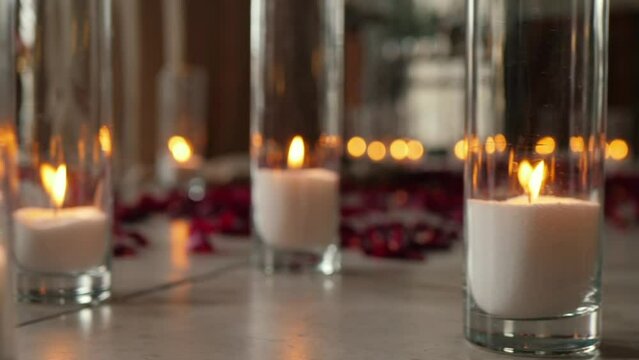 Beautiful candles on the floor burn in glass flasks