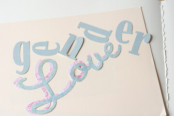 machine-cut paper sign with the words "gender" and "love" on blank paper