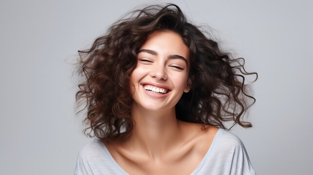 Smiling woman with long curly hair, showcasing beauty and glamour in a studio portrait