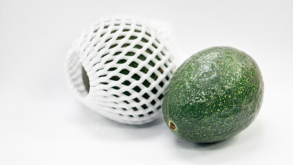 Green avocado fruit and rough skin. fruits are covered with shockproof foam with a mesh pattern for side beauty. Isolated white background.