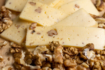 Sliced piece of milk cheese with walnuts