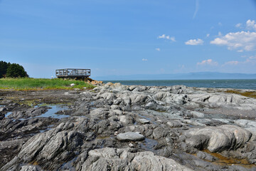 Wooden observatory platform on Island cape on a sunny day. Rocks rounded by the ocean. Ile aux Lièvres on St-Lawrence river