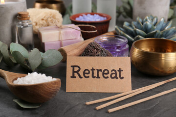 Card with word Retreat and different spa products on dark grey table