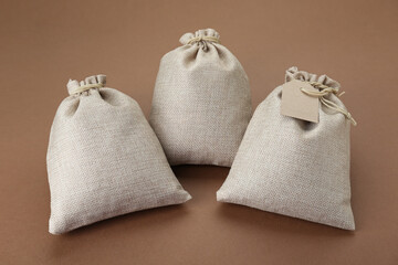 Three tied burlap bags on brown background