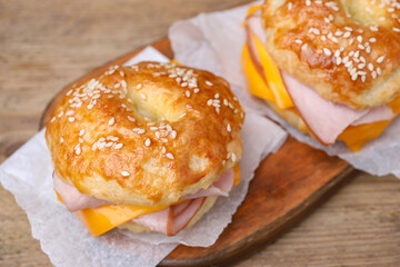 Delicious bagels with ham and cheese on wooden table, closeup