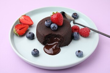 Plate with delicious chocolate fondant and berries on violet table