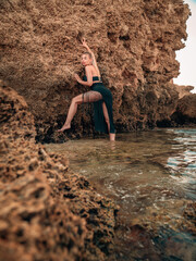 Blond Young Model Standing on the beach near rocks