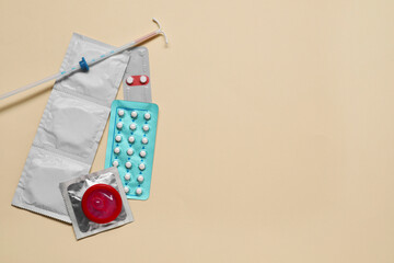 Contraception choice. Pills, condoms and intrauterine device on beige background, flat lay. Space for text