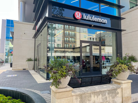 Close-up large Lululemon logo at fa&ccedil;ade entrance of store front glass door, poster and trending sportwear clothes display in urban Legacy West lifestyle center
