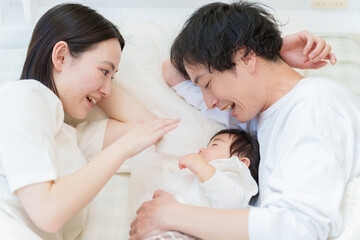 Obraz na płótnie Canvas ベッドで赤ちゃんと添い寝する夫婦