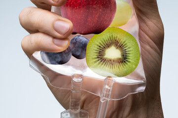 Human Hand Holding Saline Bag With Fruit Slices Over Grey Background