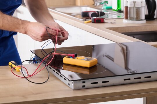 Technician Repairing Induction Stove In Kitchen
