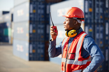 African factory worker or engineer using walkie talkie and talking about work in containers...