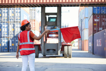 worker or engineer holding red flag in front of crane car in containers warehouse storage