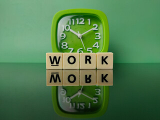 Toy word and green clock with text WORK on green background with reflection