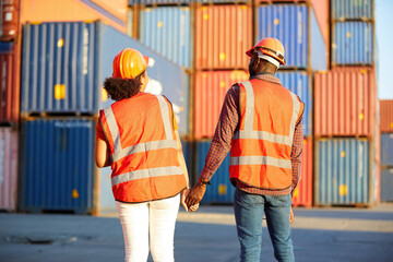 back view African factory workers or engineers holding hands and looking at containers in warehouse storage