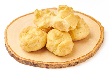 Pile of Cream puffs (Choux cream or Eclair) served on wooden plate isolated on white background....