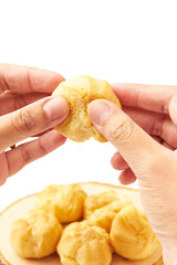 Hand Holding Cream puffs (Choux cream or Eclair) isolated on white background. Cream puffs are made with a light choux pastry that puffs up when baked. filled with vanilla cream.