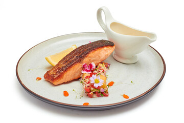 Grilled Salmon with tomato salsa and lime decorated with beautiful flowers, Served with cream salad and sliced lemon in a large porcelain plate isolated on white background.