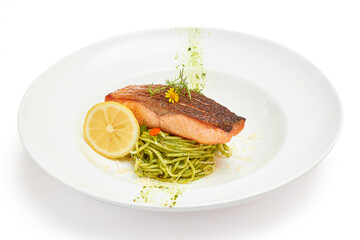 Spaghetti Pesto Sauce with grilled salmon Served with sliced lemon, beautifully decorated with flowers in white dish isolated on white background. Spaghetti with Italian Basil as the main ingredient.