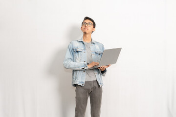 A male with his laptop standing isolated in front of white background. Indonesian or southeast...